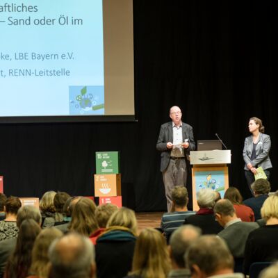 Nachhaltigkeitstagung 2018: Nachhaltigkeit first; zwei Referent*innen stehen auf der Bühne und geben einen Input
