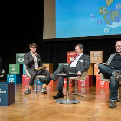 Nachhaltigkeitstagung 2018: Nachhaltigkeit first; vier Menschen sitzen auf Sesseln und tauschen sich während einer Podiumsdiskussion auf der Bühne aus