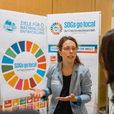 Bayerische Nachhaltigkeitstagung 2019: Handeln für den Wandel; Drei Menschen tauschen sich an einem Stand am Zukunftsmarkt aus