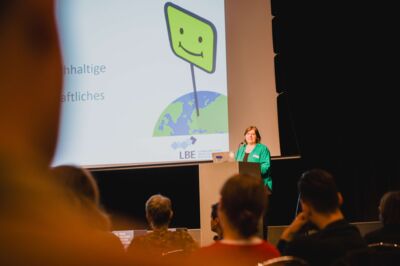 Bayerische Nachhaltigkeitstagung 2023: Nachhaltigkeit in Zeiten knapper Kassen; Danielle Rodarius eröffnet die Tagung mit Grußworten auf der Bühne