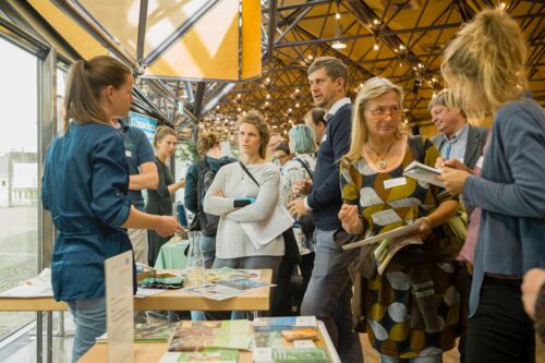 Bayerische Nachhaltigkeitstagung 2019: Handeln für den Wandel; Aufnahme an einem Stand des Zukunftsmarktes: einige Menschen tauschen sich an einem Stand aus
